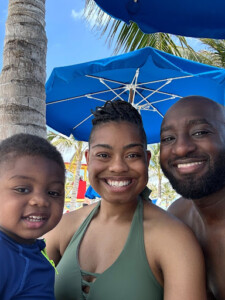 A man and woman play with a child on a sunny beach, enjoying the waves and building sandcastles together.